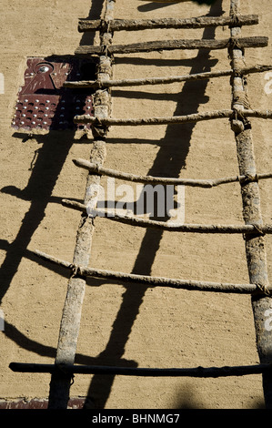 Fatte a mano scaletta di legno contro la parete di adobe; Djenné, Mali, Africa occidentale Foto Stock