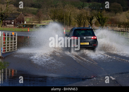 VW autoveicolo viaggia a velocità attraverso terreni inondati nel Derbyshire vicino a Bakewell Foto Stock