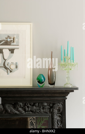 Artwork, vetreria e candelabri sulla mantelpiece intagliato Foto Stock