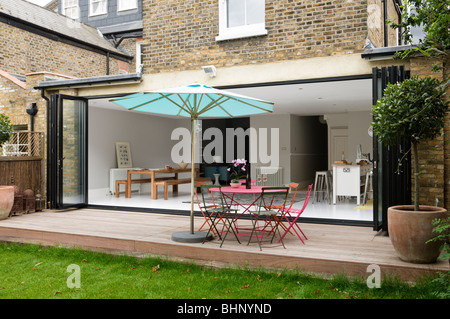 Patio arredato con ombrelloni di Londra residenza vittoriana con moderna estensione Foto Stock