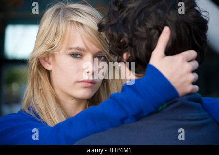 Teenage giovane ragazza braccio attorno alla sua testa guarda al ragazzo vista da dietro di lui . Modello rilasciato Foto Stock