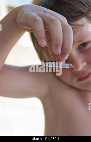 7 anno di età giovane ragazzo rammarica la morte di pesci di piccole dimensioni con un mantenimento fino alla telecamera Foto Stock