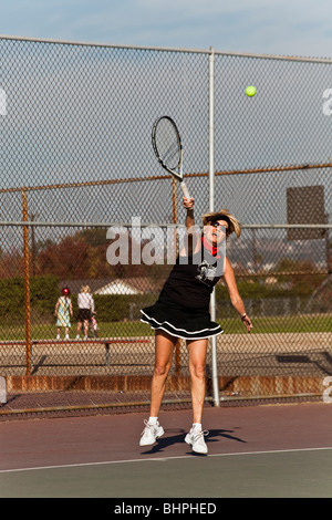 Senior donna nella sua 70s giocando a tennis nel parco pubblico. Signor © Myrleen Pearson Foto Stock