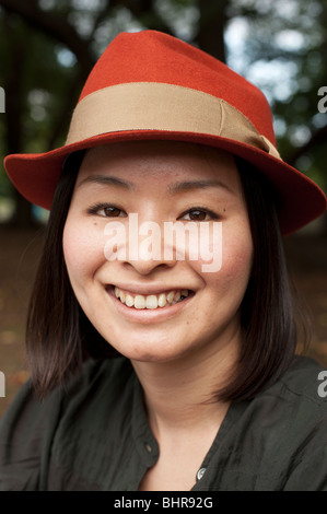 Un ritratto di una donna giapponese in un arrugginito orange hat, Tokyo, Giappone. Foto Stock