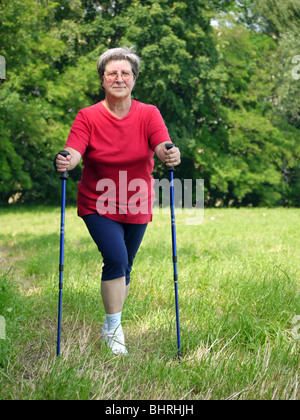 Senior donna facendo una serie di warm-up con esercizi di poli a piedi Foto Stock