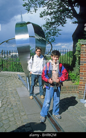 Due giovani ragazzi in piedi sul primo meridiano, Greenwich, Londra, Inghilterra Foto Stock