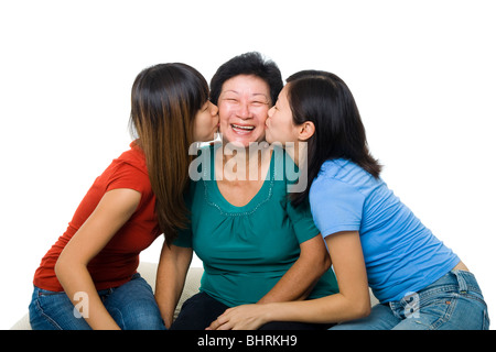 Famiglia asiatica ritratto su sfondo bianco. Figlie adulte kissing senior madre Foto Stock