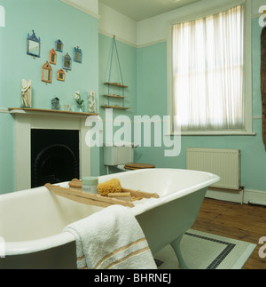 Roll-top bagno con vasca da bagno in legno-rack in verde pallido bagno con piccolo caminetto bianco e voile tenda da finestra Foto Stock