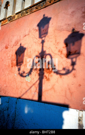 Ombra di luci di strada su una sbiadita & weathered muro color terracotta, Venezia, Italia Foto Stock