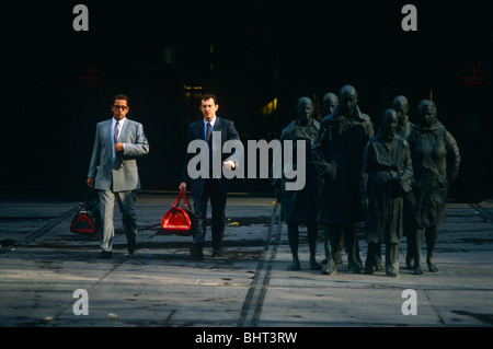 Due città ufficio lavoratori a piedi alacremente passato una serie di statue di pendolarismo anche la gente di estensione come se fare il loro modo home. Foto Stock