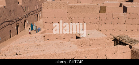 Una famiglia a piedi attraverso il mattone di fango e edifici adobe di Mhamid el Ghizlane nel sud del Marocco Foto Stock