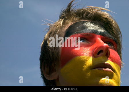 Un tedesco patriottico sostenitore di calcio con il tedesco della bandiera dipinta sulla sua faccia rivolta in alto Foto Stock