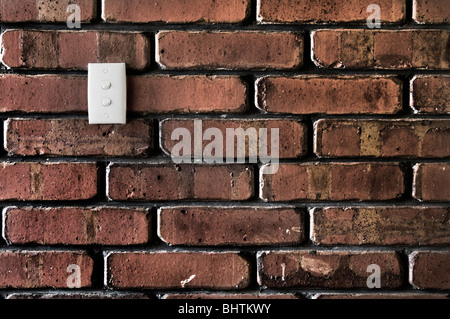 In stile grunge muro di mattoni che mostra un sacco di texture con un doppio interruttore di luce su di esso. Foto Stock