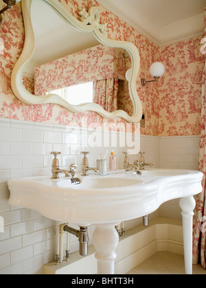 Bianco curvo specchio sopra doppia bianca in stile vittoriano di bacini nel paese bagno con rosa Toile de Jouy wallpaper Foto Stock