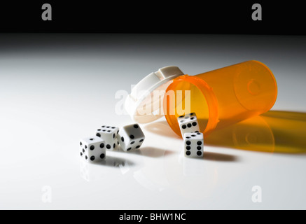 Una pillola contenitore con cinque giochi di dadi, in modo concettuale still life, il gioco d'azzardo con assistenza sanitaria o prodotti farmaceutici, Foto Stock