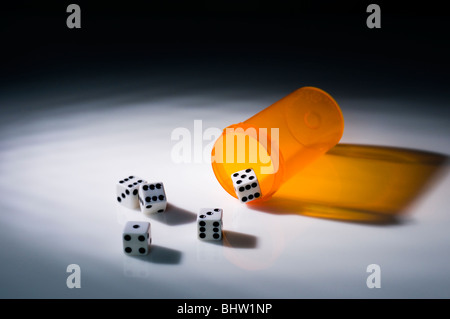 Una pillola contenitore con cinque giochi di dadi, in modo concettuale still life, il gioco d'azzardo con assistenza sanitaria o prodotti farmaceutici, Foto Stock