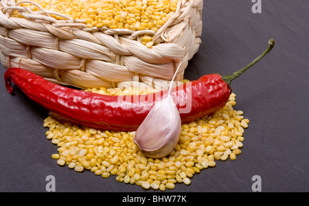 Speziato curry di lenticchie ingredienti di lenticchie giallo, rosso peperoncino e aglio su ardesia scuro dello sfondo. Foto Stock