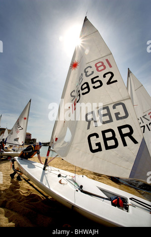 L'uomo spingendo solo vela dinghy sulla spiaggia di Calella de Palafrugell, Catalogna, Spagna Foto Stock