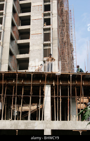 Poveri Lavoratori pericolosamente a bordo della struttura in un alto edificio costruzione senza misure di sicurezza Foto Stock