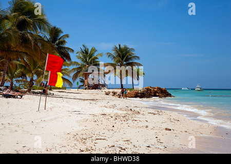 La spiaggia di Pigeon Point Tobago con cielo blu sole tropicale con il rosso e il giallo lifeguard bandiere sul display. Foto Stock