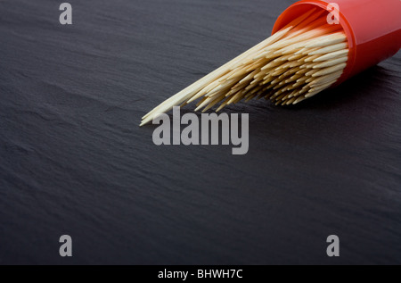 Cocktail Sticks fuoriuscita dal contenitore su ardesia scuro dello sfondo. Foto Stock