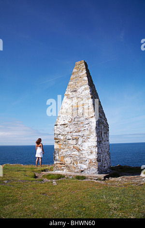 La donna stava guardando il mare accanto al faro costiero a Porthgain, lungo il Pembrokeshire sentiero costiero in West Wales, Regno Unito Foto Stock