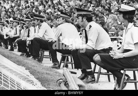 Una linea di poliziotti e di controllo delle donne il Newcastle United fans presso il St James Park 21 agosto 1976 problemi sulle strade di Newcastle quando Sunderland è arrivato in città durante gli anni settanta. Polizia montata ripristinare l'ordine mentre un cane di polizia assume un gustoso boccone di una ventola della gamba dei pantaloni! Controllo gradualmente è stata ritrovata all'interno di stadi. A St James Park un enorme la presenza della polizia è stato necessario per alcuni mentre - e avevano un loro mini-sgabelli per godersi l'azione! Foto Stock