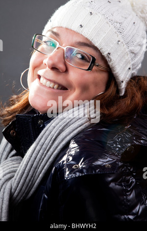 Donna matura con gli occhiali, cappello, sciarpa e pesante cappotto invernale Foto Stock