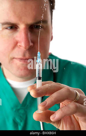 Uomo che indossa medical scrubs e stetoscopio in azienda ago e siringa contenente il liquido squirting Foto Stock