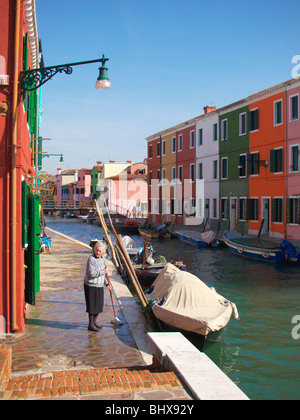 Signora anziana pulisce il percorso al di fuori della sua hous nel colorato villaggio di pescatori di Burano Venezia Italia Foto Stock