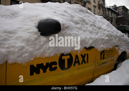 Un parcheggiato New York City taxi ricoperta di neve nel West Village quartiere di New York Foto Stock