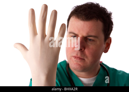 Uomo che indossa medical scrubs e stetoscopio mettendo su un paio di guanti di gomma Foto Stock