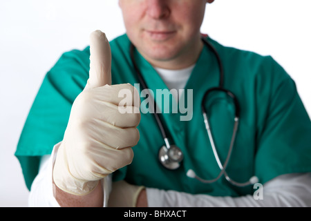 Uomo che indossa medical scrubs e uno stetoscopio che mostra Thumbs up gesto di successo Foto Stock
