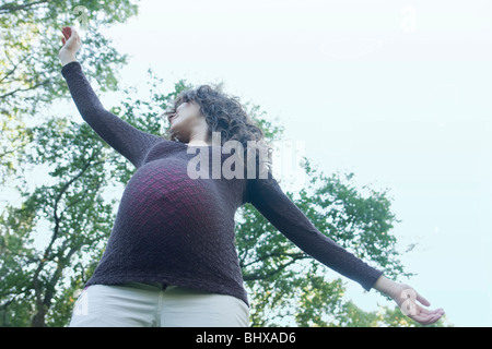 Basso angolo di molto la donna incinta con le braccia aperte, Manitoba, Canada Foto Stock