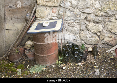 Pasticcio costituito da vecchie scope, fioriere, un tamburo di olio e vino-bottiglie vicino all'entrata di una casa in Rémuzat, Drôme, Francia Foto Stock
