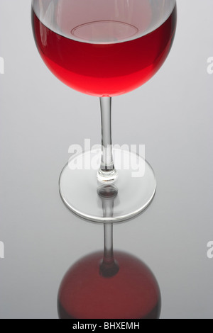 Vino rosso in un bicchiere vicino su uno sfondo grigio con la riflessione Foto Stock