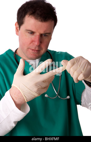 Uomo che indossa medical scrubs e stetoscopio mettendo su un paio di guanti di gomma Foto Stock