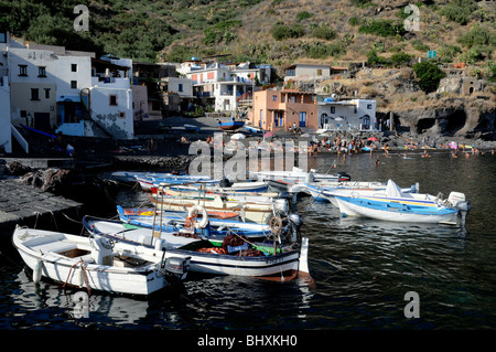 Ancorate piccole barche a motore e la gente sulla spiaggia nel villaggio sul mare di Rinella, su le Eolie isola di Salina, Sicilia, Italia. Foto Stock