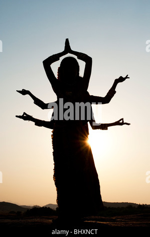 Silhouette di tre ragazze indiano in una classica sei armati dea Indù pongono al tramonto. India Foto Stock