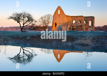 Newark Priory riflessa nel fiume Wey Pyrford. Presto la luce del sole catture la muratura in pietra lungo il gelido riverbank Foto Stock