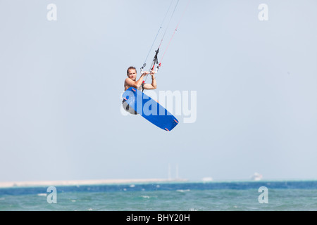 Kiteboarder navigare in acque blu e salti in aria in alto. Foto Stock