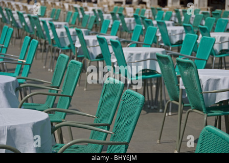 Tavoli e sedie appartenenti ai caffè sulla Piazza San Marco, tutti allineati e in attesa per il business. Foto Stock