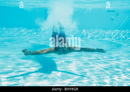 Uomo di nuoto con gli occhi aperti sott'acqua in piscina Foto Stock