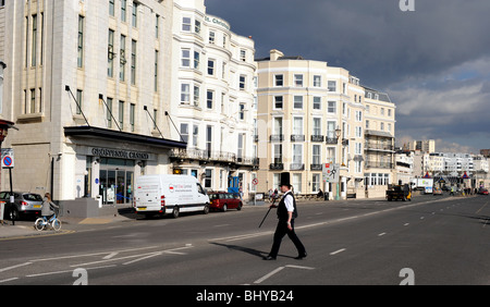 Uomo con enorme cappello alto attraversando la strada lungo il lungomare di Brighton Regno Unito Foto Stock