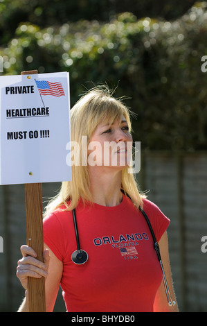 Assistenza sanitaria privata negli Stati Uniti devono andare manifestante femmina tenendo uno stetoscopio & Avvisi di protesta Foto Stock