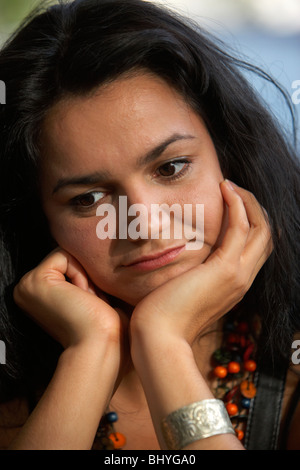 A metà degli anni venti donna ispanica in appoggio il suo mento sul suo palms seduto annoiato in attesa Foto Stock