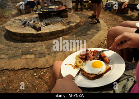 Limpopo, Sud Africa, i turisti su safari godendo di bush prima colazione cotta sul fuoco di campo, cibo, pasto Foto Stock