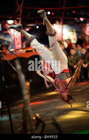 Una giovane donna il bilanciamento capovolto sul filo allentato, non montare il circo di stato eseguendo, Wales UK Foto Stock