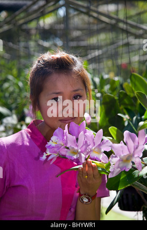 Serra di piante e fiori. Donna asiatica in abito tradizionale, lo sniffing fragrante orchidee in Bai Fattoria delle Orchidee, Chiang Mai nel nord della Thailandia, Asia Foto Stock