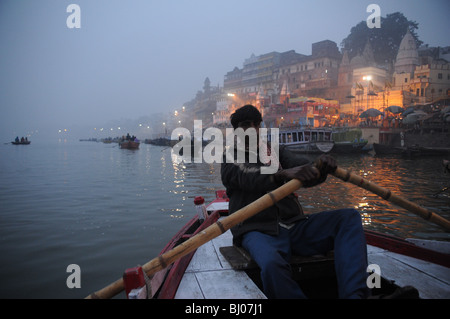 Un giovane uomo righe passato Varanasi è sacro ghats lungo il fiume Gange appena prima del sorgere del sole Foto Stock